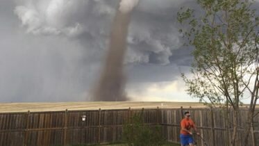 Man mowing lawn with tornado behind created webstorm